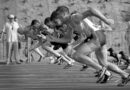 athletes running on track and field oval in grayscale photography