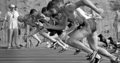 athletes running on track and field oval in grayscale photography